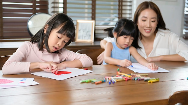 Familia asiática con niños Dibujar y pintar en la mesa en la sala de juegos en casa Juego educativo