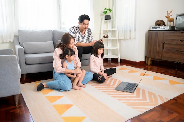 Familia asiática con niños usando computadora portátil en casa