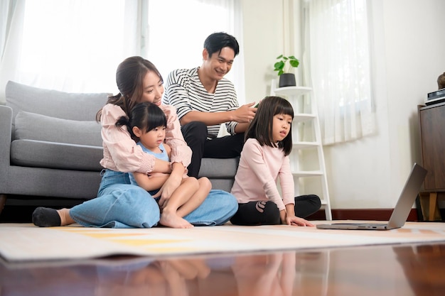 Familia asiática con niños usando computadora portátil en casa