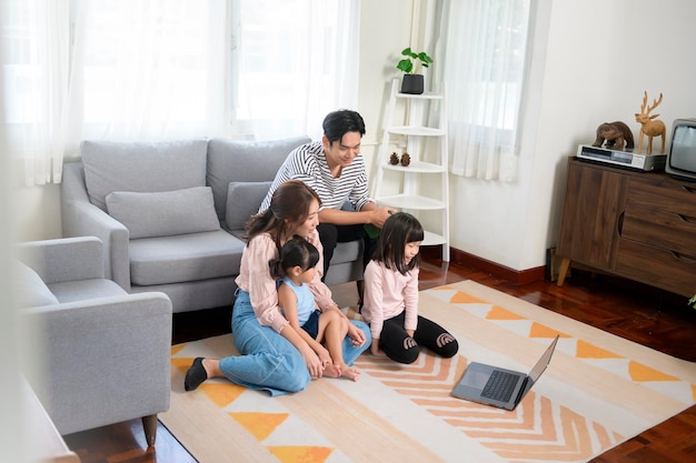 Familia asiática con niños usando computadora portátil en casa