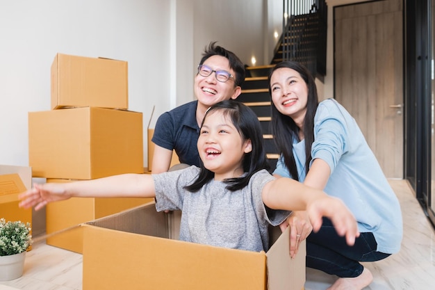 Familia asiática que se muda a un nuevo apartamento con muchas cajas de embalaje
