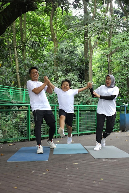 Família asiática se divertindo praticando esporte juntos no parque.