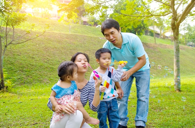 Familia asiática soplando burbujas al aire libre