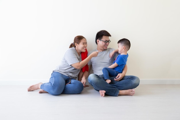 Família asiática sorrindo e sentados juntos no chão. conceito de família jovem tailandês