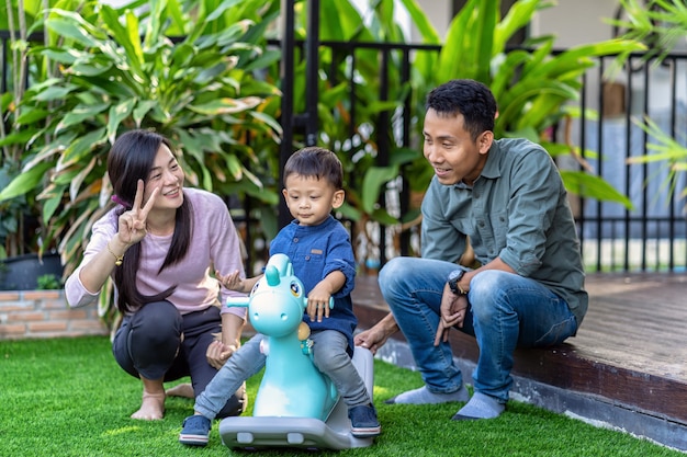 Familia asiática con su hijo están jugando con un juguete juntos cuando viven en el jardín delantero de una casa moderna