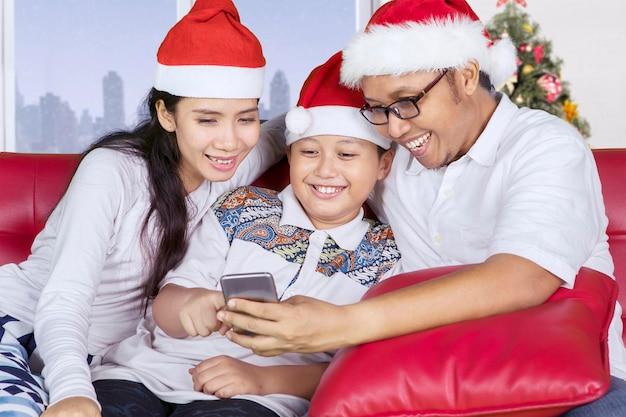 Familia asiática con un teléfono inteligente en Navidad