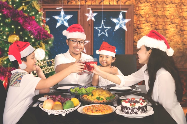 Foto la familia asiática está tostada juntos en la mesa del comedor