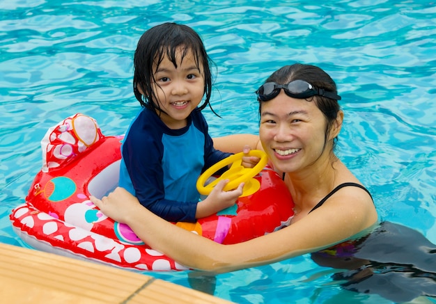 Familia asiática en el tubo de baño jugando en la piscina