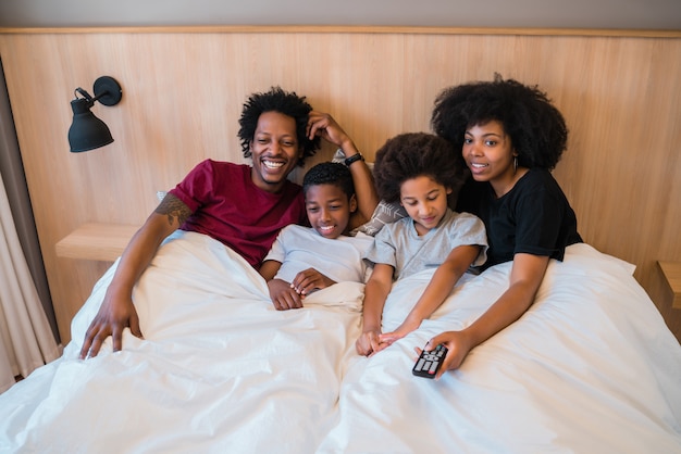 Foto família assistindo a um filme na cama em casa.