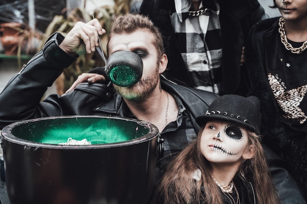 Família assustadora mãe pai filhas comemorando o dia das bruxas Caldeirão de poção Terrível maquiagem de meia face de caveira negratrajes de bruxa imagens elegantesTerror diversão na festa infantil no celeiro na rua