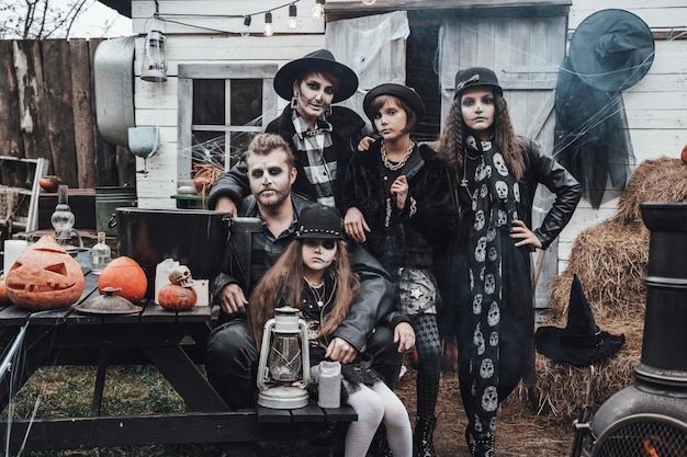 Família assustadora mãe pai filhas comemorando o halloween Terrível maquiagem de meia face de caveira preta e fantasias de bruxa imagens elegantesHorrordiversão na festa infantil no celeiro na ruaHatsjackets