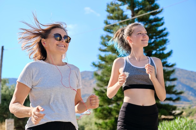 Familia atlética activa, madre e hija adolescente corriendo juntos en una carretera al aire libre. Estilo de vida saludable, deporte, comunicación de padres e hijos adolescentes.