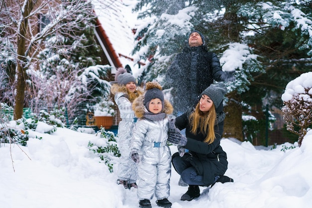 Família atraente se divertindo no parque de inverno. Os pais passam o tempo ao ar livre com as crianças brincando juntas