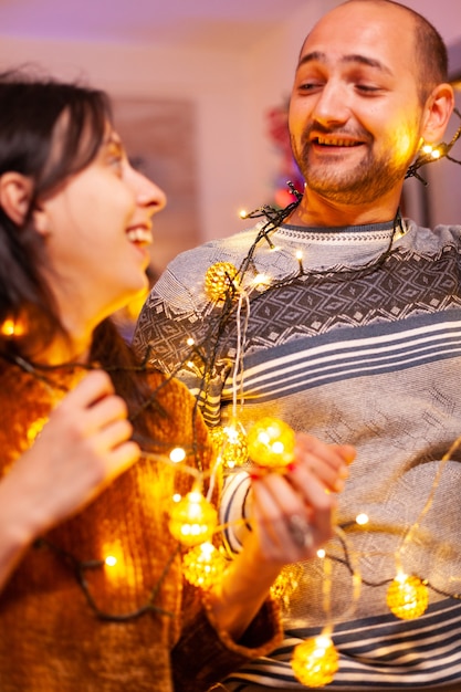Familia atrapada en las luces del árbol de Navidad en la cocina decorada de Navidad