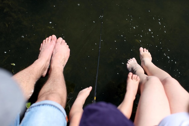 Familia bañándose y salpicando agua con el pie en un lago en verano