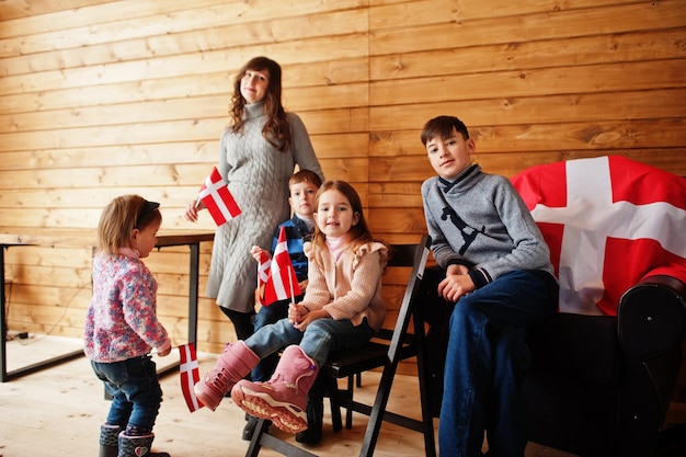 Familia con banderas de Dinamarca dentro de una casa de madera Viajar a los países escandinavos Los daneses más felices