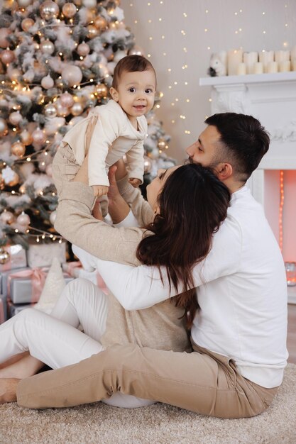 Foto una familia con un bebé delante de un árbol de navidad