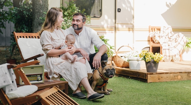 Foto familia con bebé y perro cerca de autocaravana, viajando