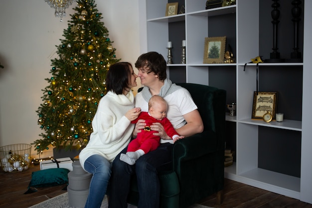 Familia besándose cerca del árbol de navidad bellamente decorado, navidad