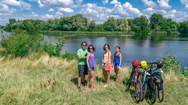 Familia en bicicleta en bicicleta al aire libre, padres activos e hijos en bicicleta, vista aérea superior de una familia feliz con niños que se relajan cerca del hermoso río desde arriba, concepto de deporte y fitness