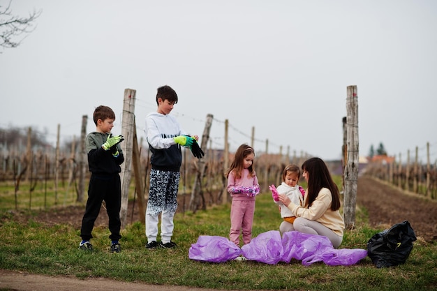 Familia con bolsa de basura recogiendo basura mientras limpia en los viñedos Conservación ambiental y reciclaje ecológico