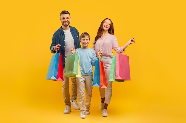 Familia con bolsas de compras en fondo amarillo