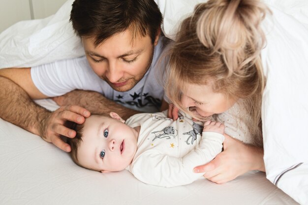 Família bonita na cama. pais brincando com seu bebê