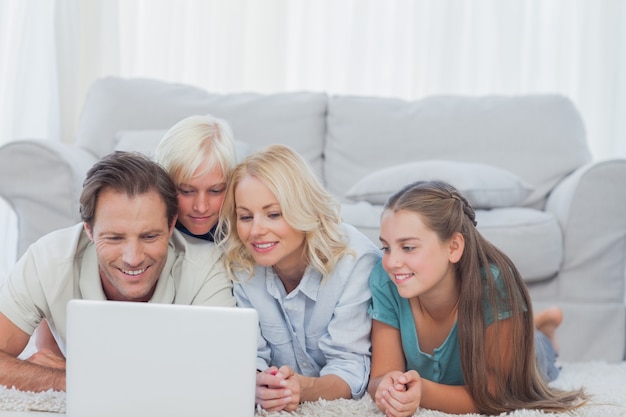 Família bonita usando um laptop deitado em um tapete