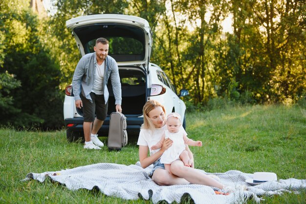 Familia en un bosque. Gente en el coche. Fondo de puesta de sol.