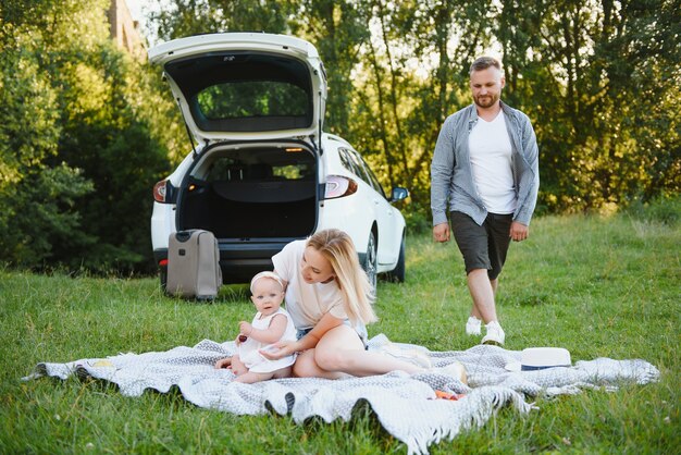 Familia en un bosque. Gente en el coche. Fondo de puesta de sol.