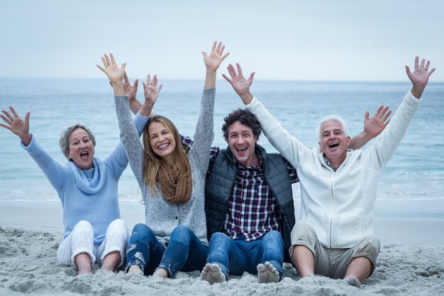 Familia con los brazos levantados sentado a la orilla del mar