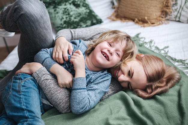 Família brincalhão. Mãe e bebê rindo na cama