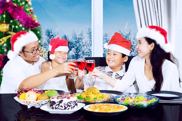 Familia brinda vasos de bebidas en la cena de Navidad