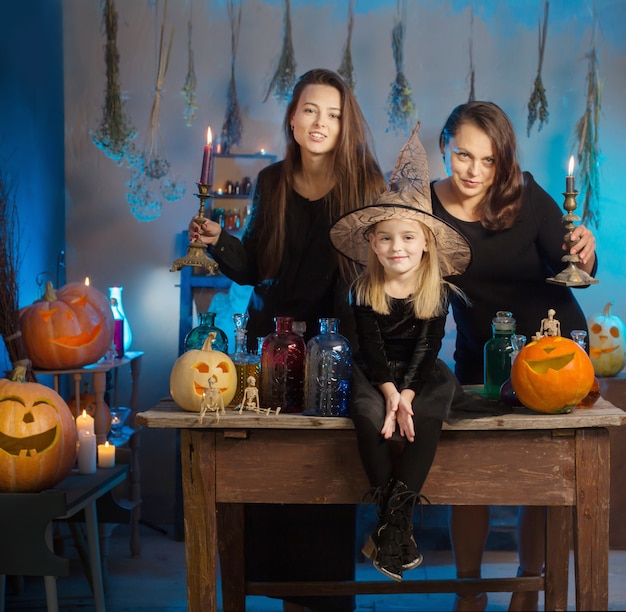 Familia de brujas con pociones y calabazas de Halloween en casa