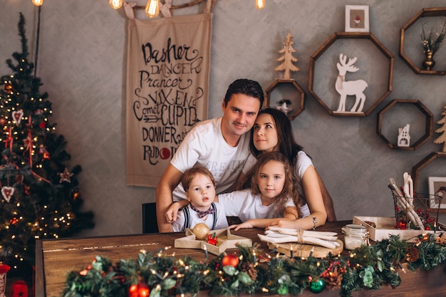 Família cacasian feliz na casa de férias aconchegante decorada com luzes de Natal. Pais e filhos alegres são festas tradicionais comemoradas