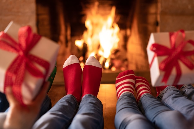 Familia en calcetines de Navidad junto a la chimenea Madre padre e hijos divirtiéndose juntos