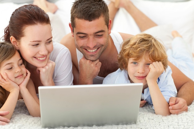 Familia en la cama jugando con una computadora portátil