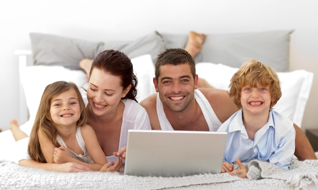 Familia en la cama usando una computadora portátil