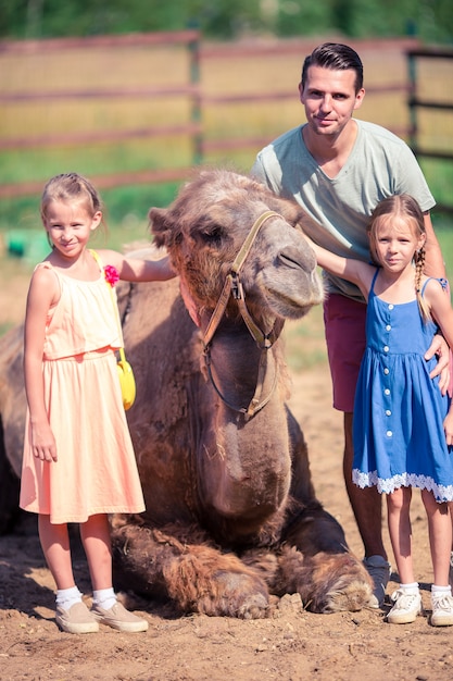 Familia con camellos en el zoológico en un cálido y soleado día de verano.