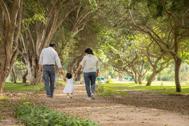 Foto una familia camina por un camino en un parque con una niña