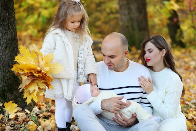 La familia camina sobre las hojas de otoño.