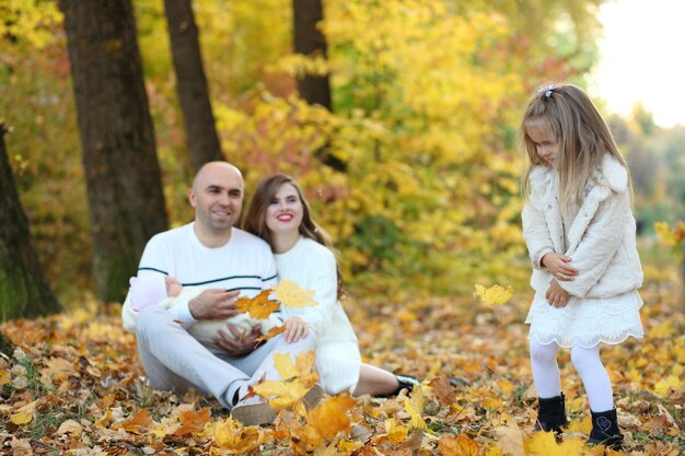 La familia camina sobre las hojas de otoño.