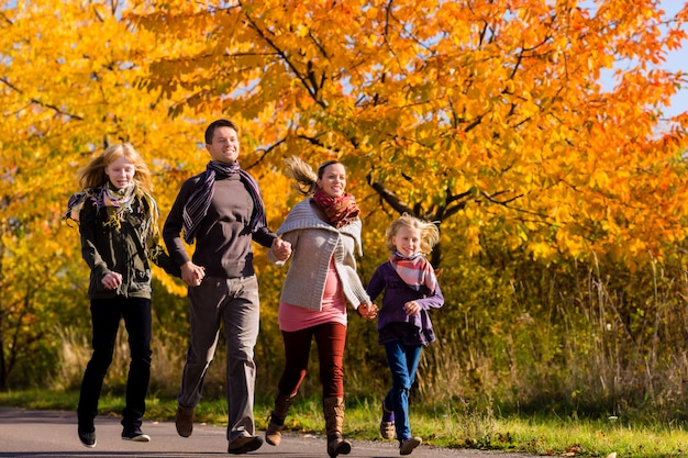 Familia caminando delante de coloridos árboles en otoño