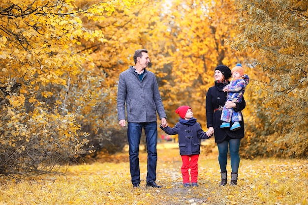 Familia caminando con niños en el parque de otoño por la tarde