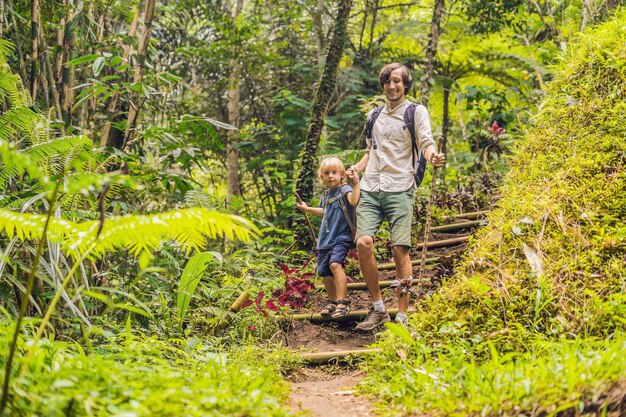 Familia en caminatas. Papá e hijo caminando en el bosque con bastones de trekking.