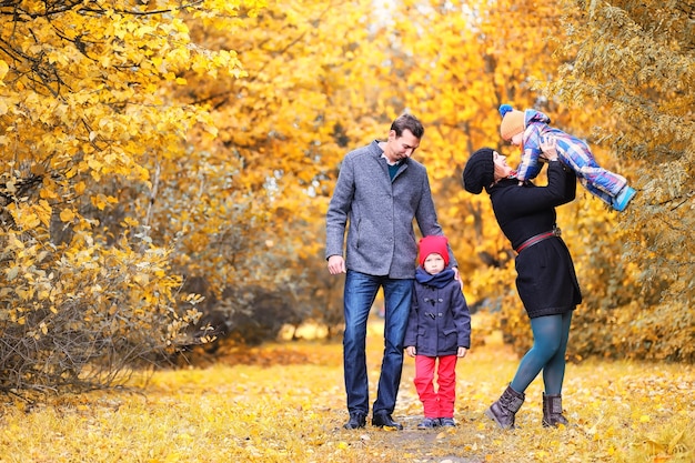 Família caminhando com crianças no parque de outono à tarde