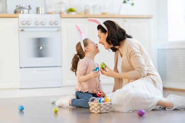 Familia cariñosa feliz está preparando panadería juntos. Madre e hija están cocinando galletas y divirtiéndose en la cocina. Niña dando a mamá ramo de flores.