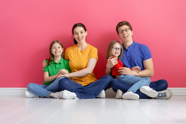 Familia cariñosa feliz. Hijas de madre, padre e hijos sobre fondo rosa.