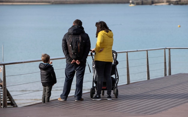 Familia con carro de bebé, mirando al mar