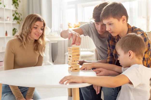 Familia en casa juega con entusiasmo un juego de mesa hecho de bloques rectangulares de madera